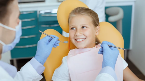 A young girl smiling at her dentist while sitting in a dental exam chair