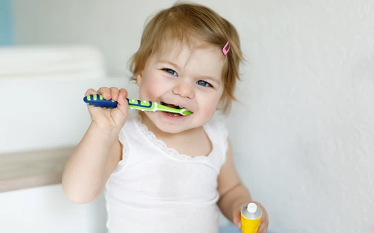 A toddler brushing her teeth and giggling